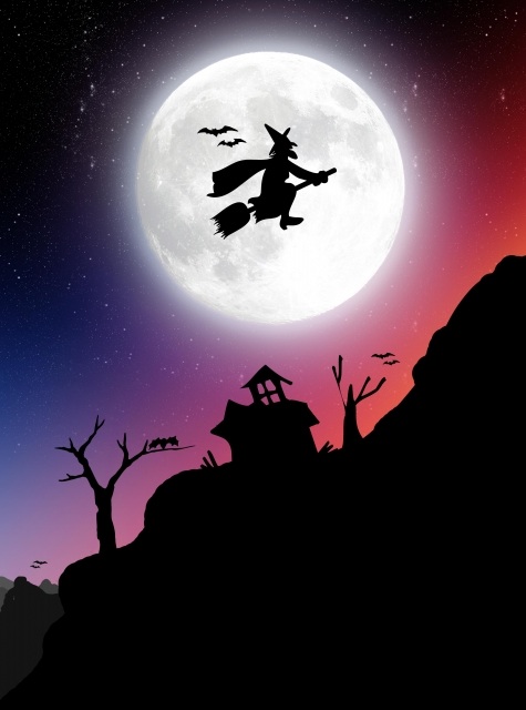 A witch flies past the full moon on halloween.